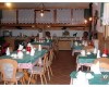 Restaurace s dřevěnými stoly a židlemi, prostřeno ubrusem a čajovými soupravami.
